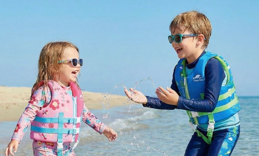 Two children in swim vests playing in shallow sea water